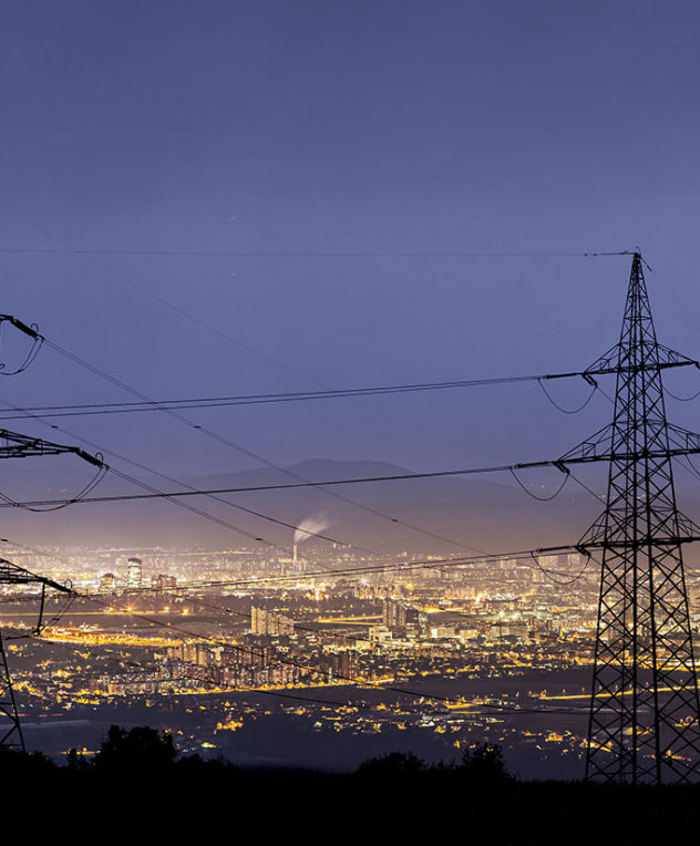 Power lines overlooking a factory at night time