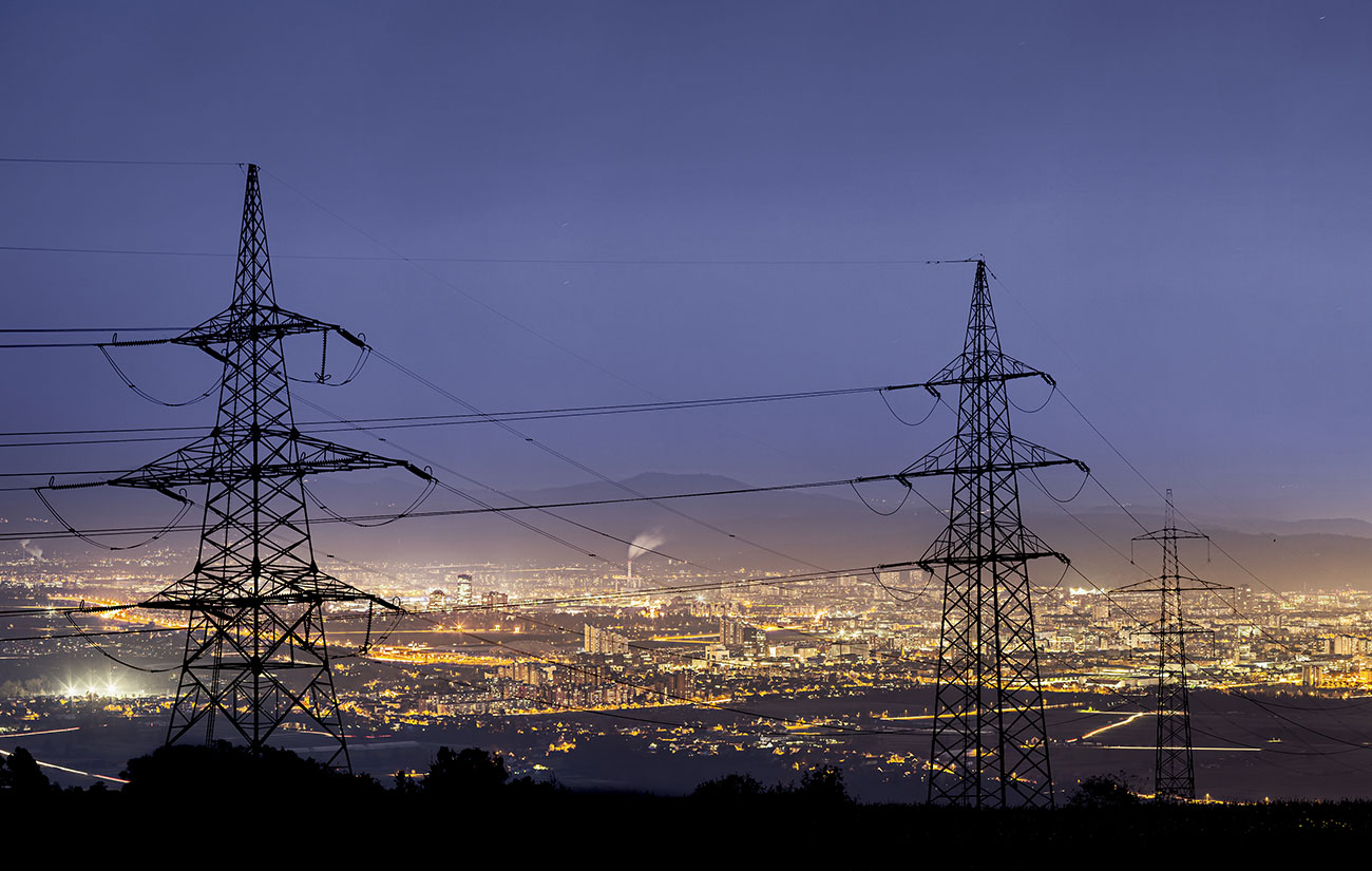 Power lines overlooking a factory at night time